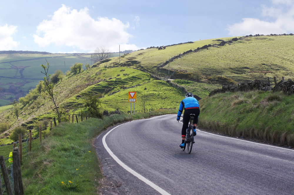 Ampere electric bike being ridden along a scenic road through the Yorkshire Dales countryside. The Ultimate 2026 Ampere Guide To Hidden Cycling Routes In The UK